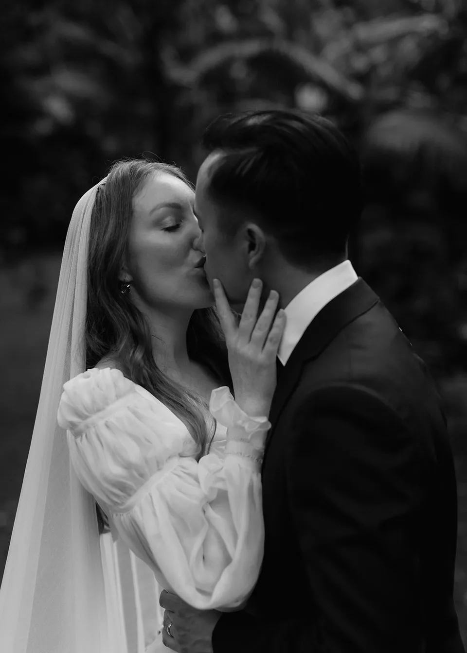 Black-and-white close portrait of the couple kissing. At Fig Tree Villa in Ewingsdale, Byron Bay, for an Elopement Collective elopement. Photograph by Bulb Creative.