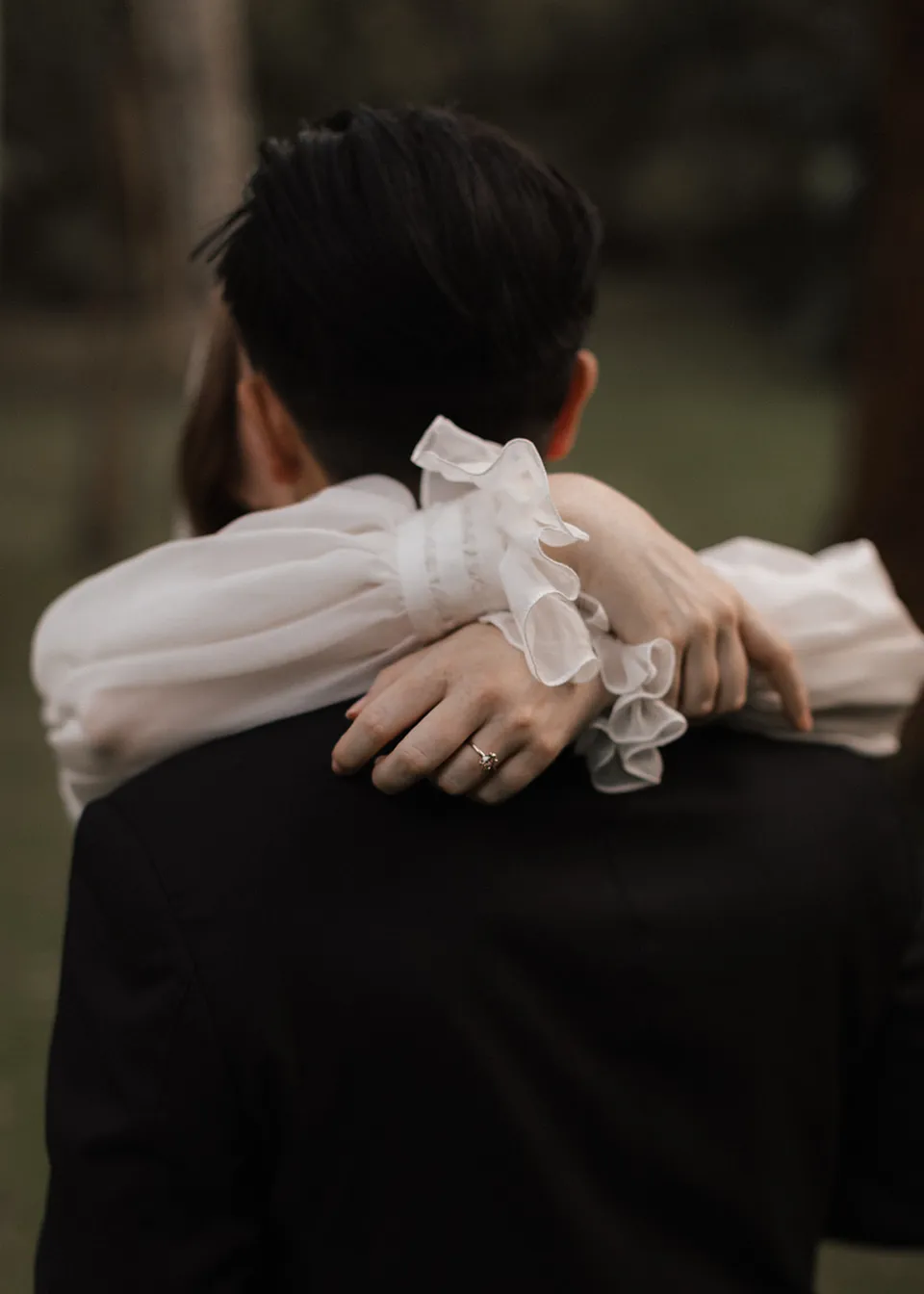 Close-up of Elyse's hands resting on Jonathan's shoulders. At Fig Tree Villa in Ewingsdale, Byron Bay, for an Elopement Collective elopement. Photograph by Bulb Creative.