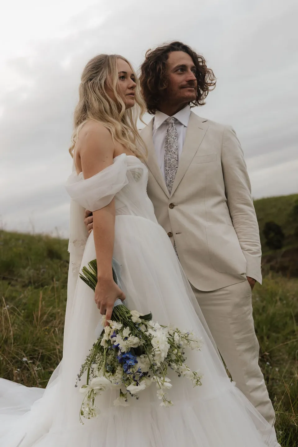 Bridget and James standing shoulder to shoulder against the open sky. At Cudgera Creek in northern New South Wales, for an Elopement Collective elopement. Photograph by Bulb Creative.