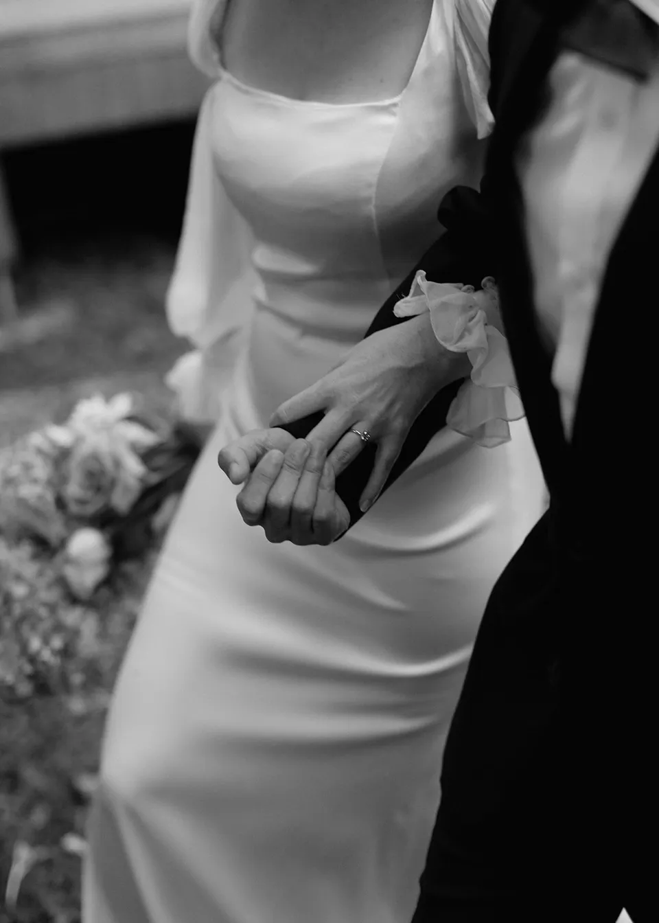 Black-and-white detail of the couple's hands and Elyse's fitted dress. At Fig Tree Villa in Ewingsdale, Byron Bay, for an Elopement Collective elopement. Photograph by Bulb Creative.