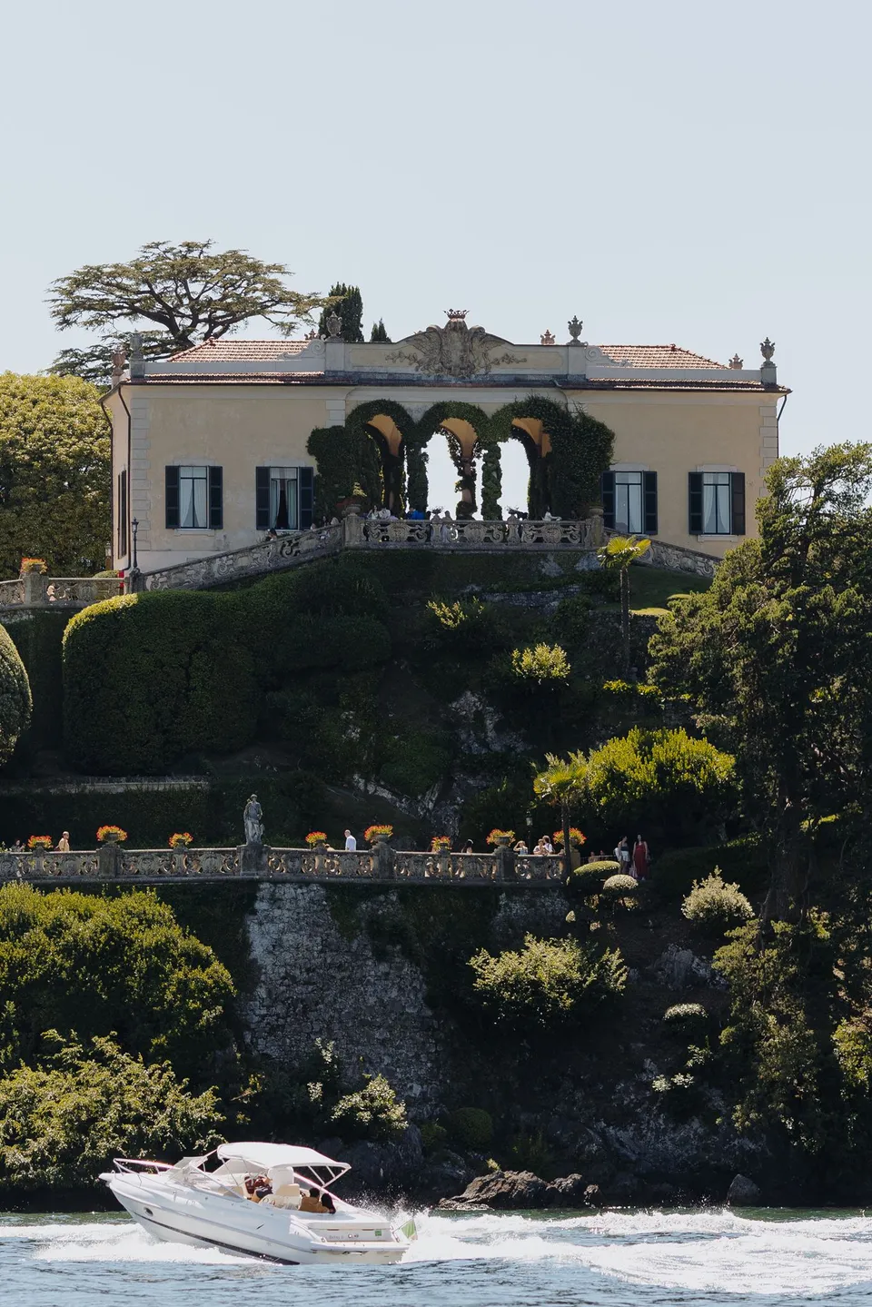 Villa del Balbianello’s lakeside loggia and gardens above a boat’s wake during the approach by water, at Lake Como in Lombardy, Italy, for an Elopement Collective elopement. Photograph by George Bowden.