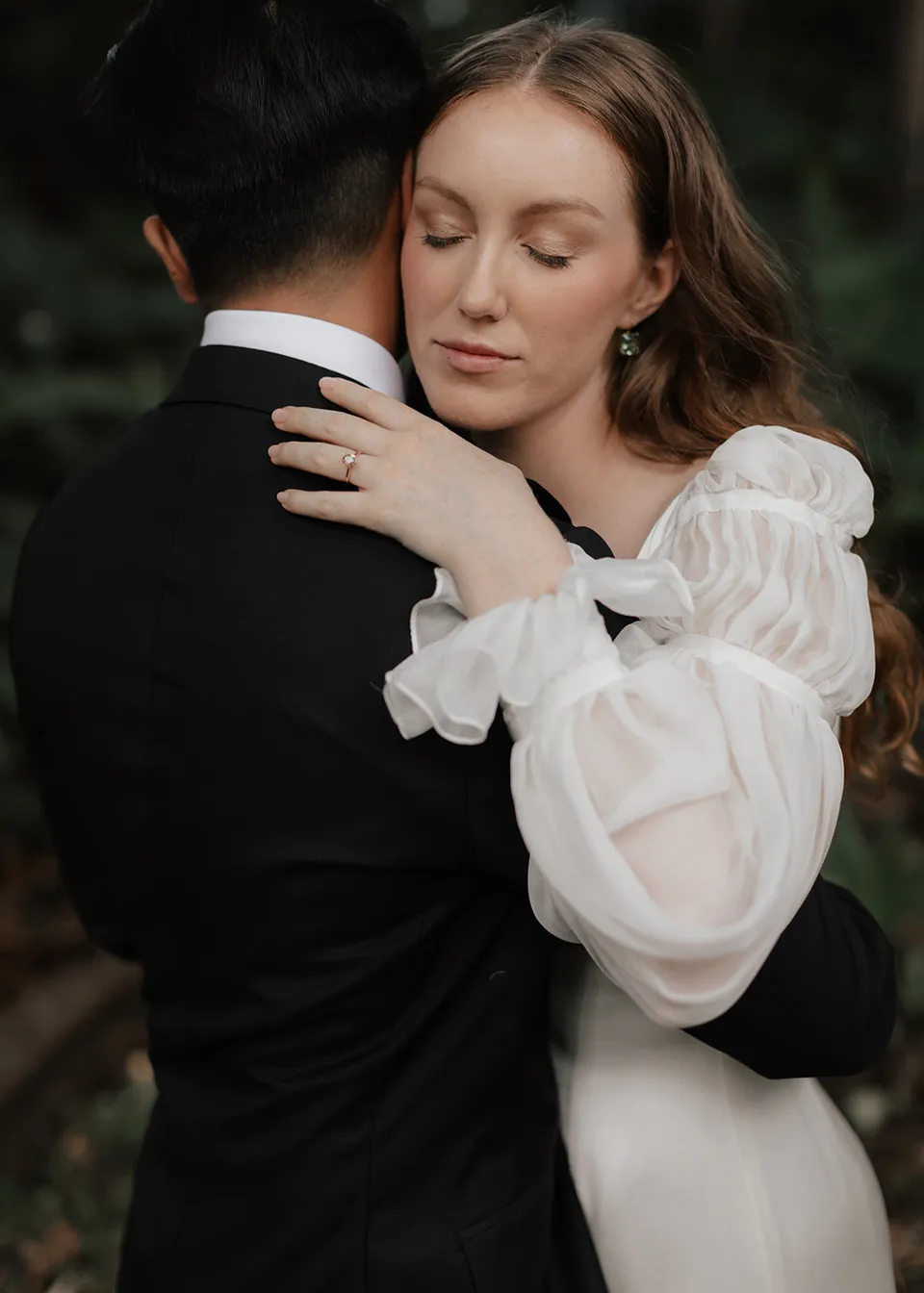 Elyse embracing Jonathan with her eyes closed. At Fig Tree Villa in Ewingsdale, Byron Bay, for an Elopement Collective elopement. Photograph by Bulb Creative.