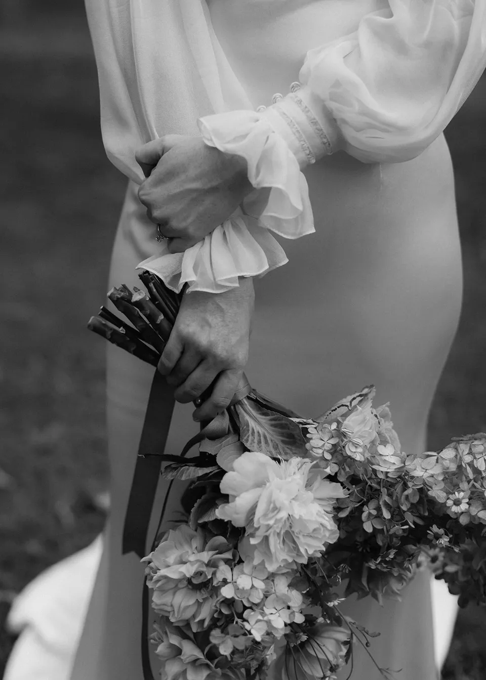 Black-and-white detail of Elyse's hands around the bouquet stems, with flowers by The Perfect Party Co. At Fig Tree Villa in Ewingsdale, Byron Bay, for an Elopement Collective elopement. Photograph by Bulb Creative.