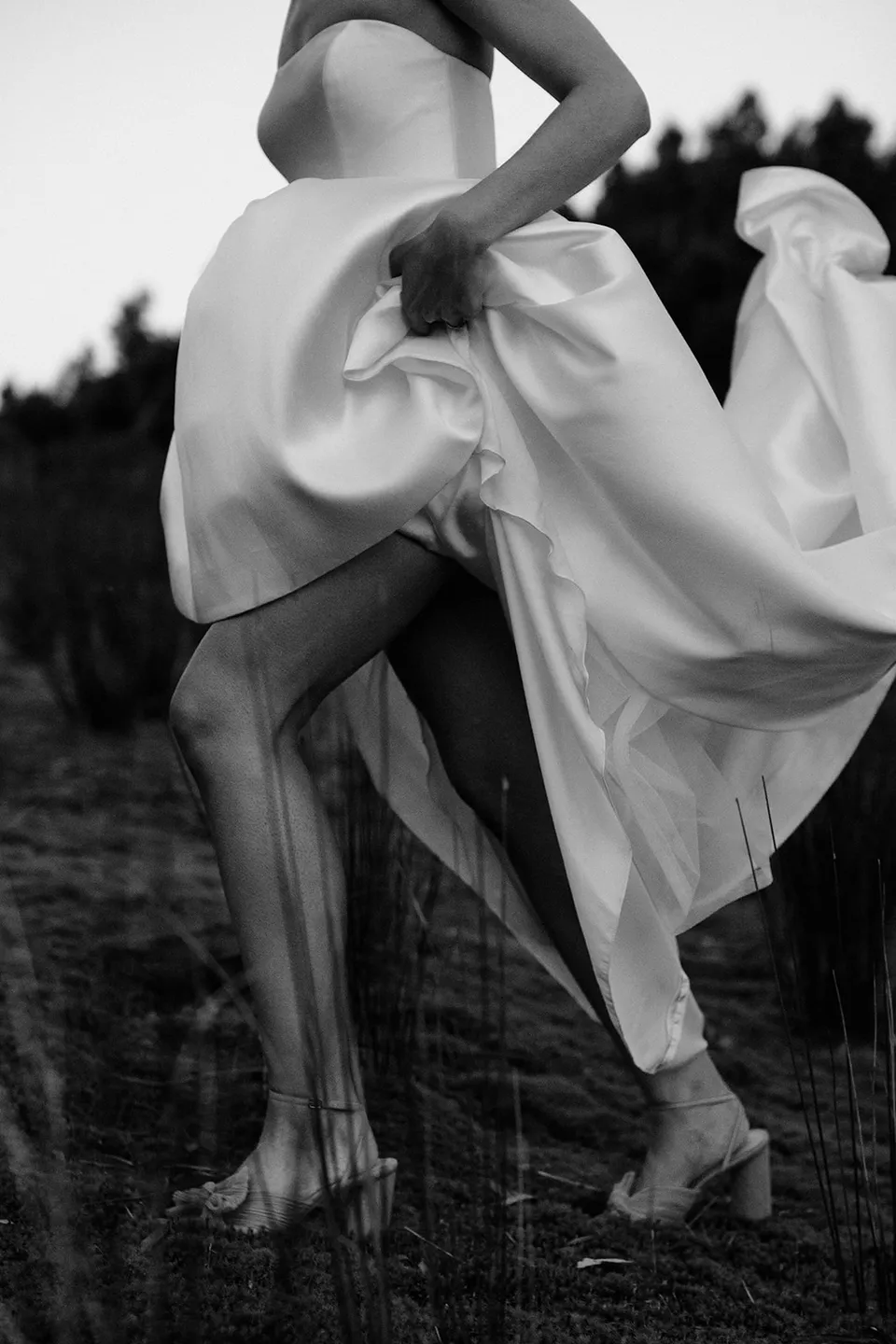 Black and white detail of Meg’s shoes and legs beneath the lifted, moving folds of her wedding dress. At The Keep on Tasmania’s east coast, for an Elopement Collective elopement. Photograph by Jenna Agius.