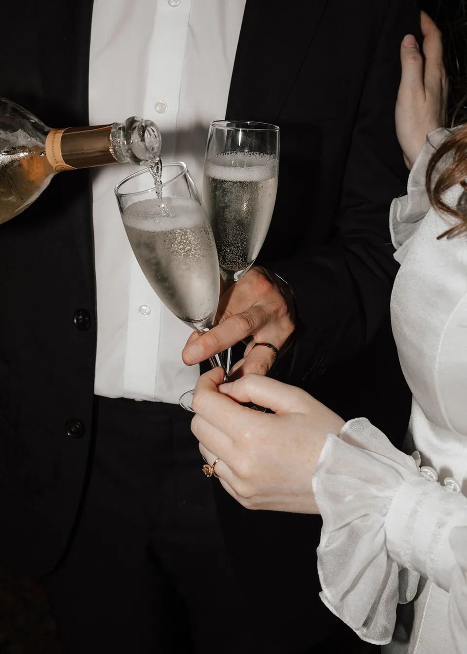 Close-up of sparkling wine being poured into the couple's glasses. At Fig Tree Villa in Ewingsdale, Byron Bay, for an Elopement Collective elopement. Photograph by Bulb Creative.