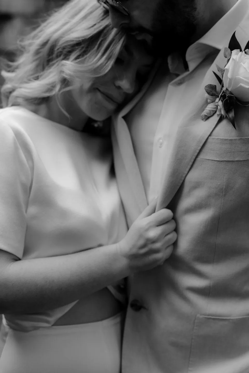 Black and white close-up of Jemmah laughing against Jack’s jacket, at Thalia Haven on the East Coast of Tasmania, Australia, for an Elopement Collective elopement. Photograph by Joey Willis.