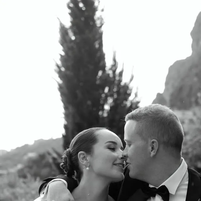 A black-and-white close-up of a couple leaning in for a kiss.