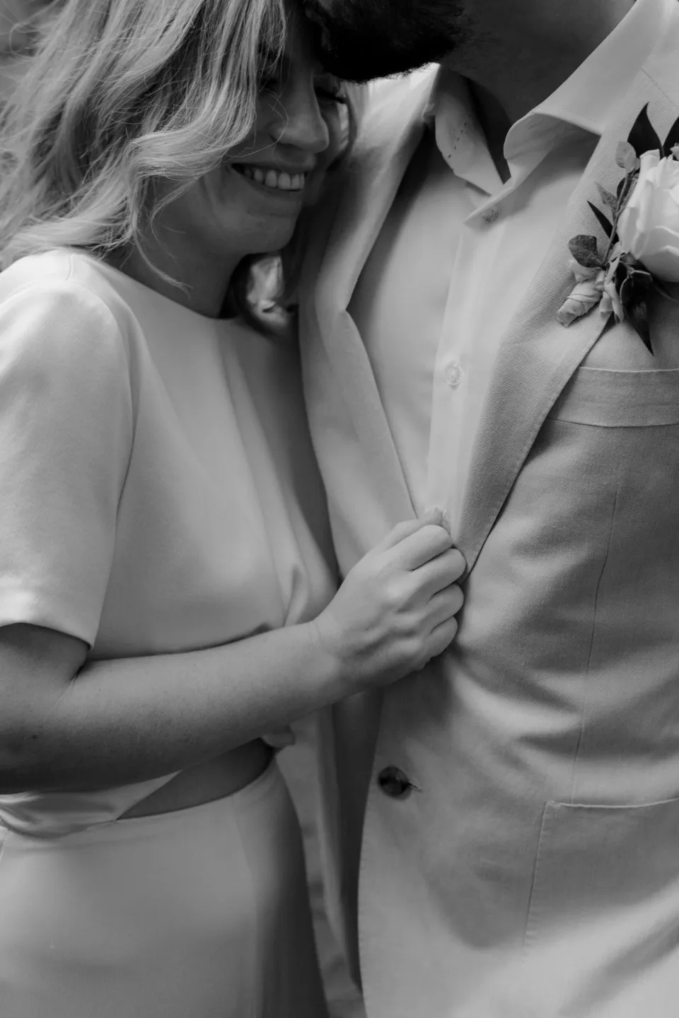 Black and white close portrait of Jemmah smiling in Jack’s embrace, at Thalia Haven on the East Coast of Tasmania, Australia, for an Elopement Collective elopement. Photograph by Joey Willis.