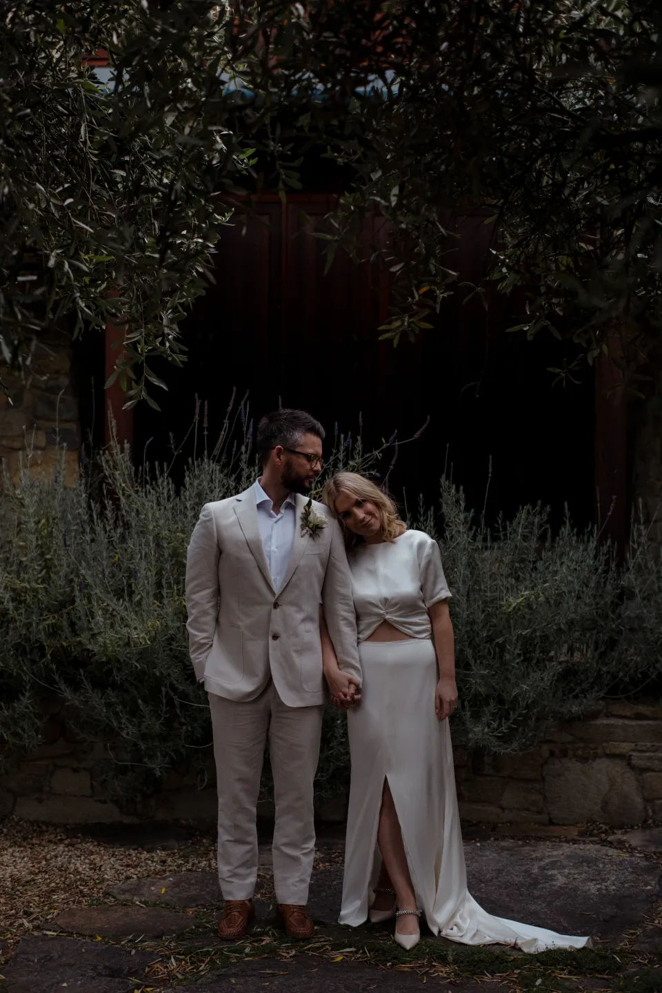 Jack kissing Jemmah’s forehead in the stone courtyard, at Thalia Haven on the East Coast of Tasmania, Australia, for an Elopement Collective elopement. Photograph by Joey Willis.