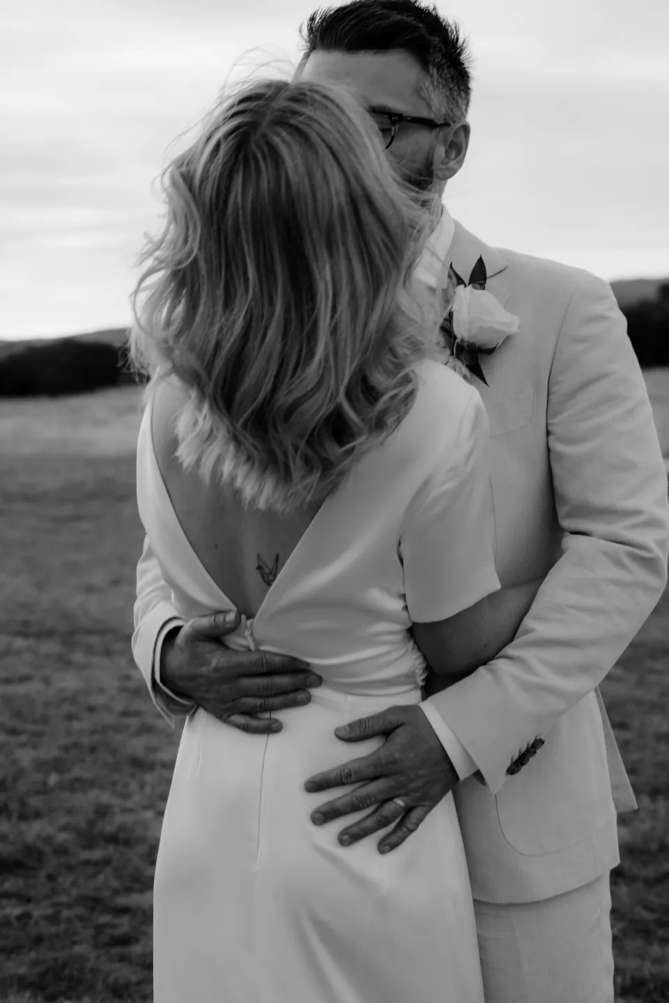 Black and white close portrait of Jack holding Jemmah as they lean together, at Thalia Haven on the East Coast of Tasmania, Australia, for an Elopement Collective elopement. Photograph by Joey Willis.