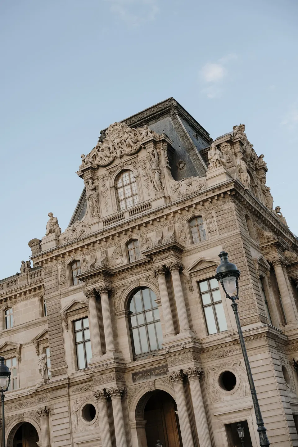 The Louvre’s ornate stone facade and slate roof against a blue sky, at the Louvre in Paris, France, during an Elopement Collective elopement. Photograph by George Bowden.