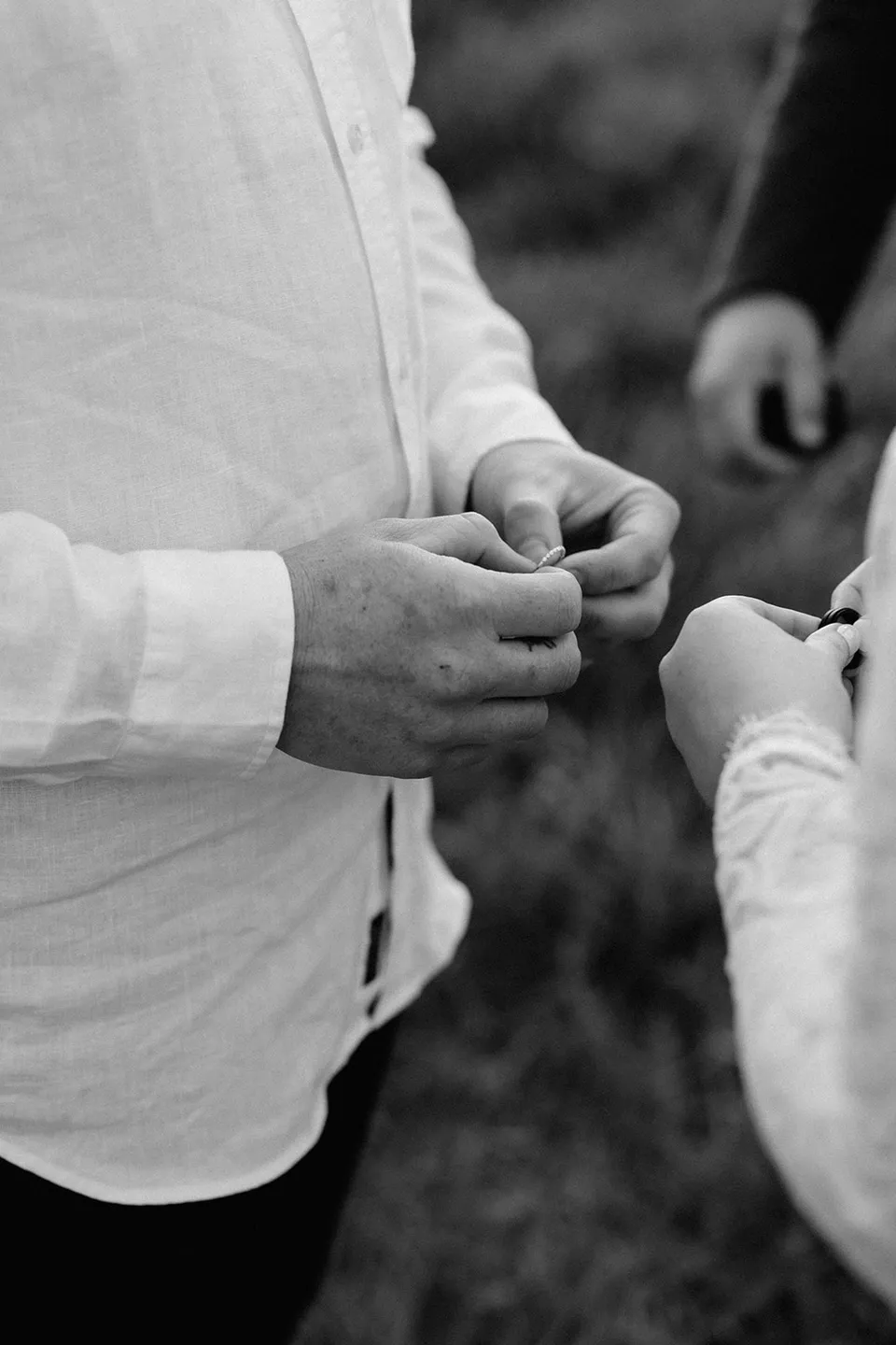 A black and white detail of Matt preparing a wedding ring during the ceremony, in the Tweed Valley, NSW, for an Elopement Collective elopement. Photo by Bulb Creative.
