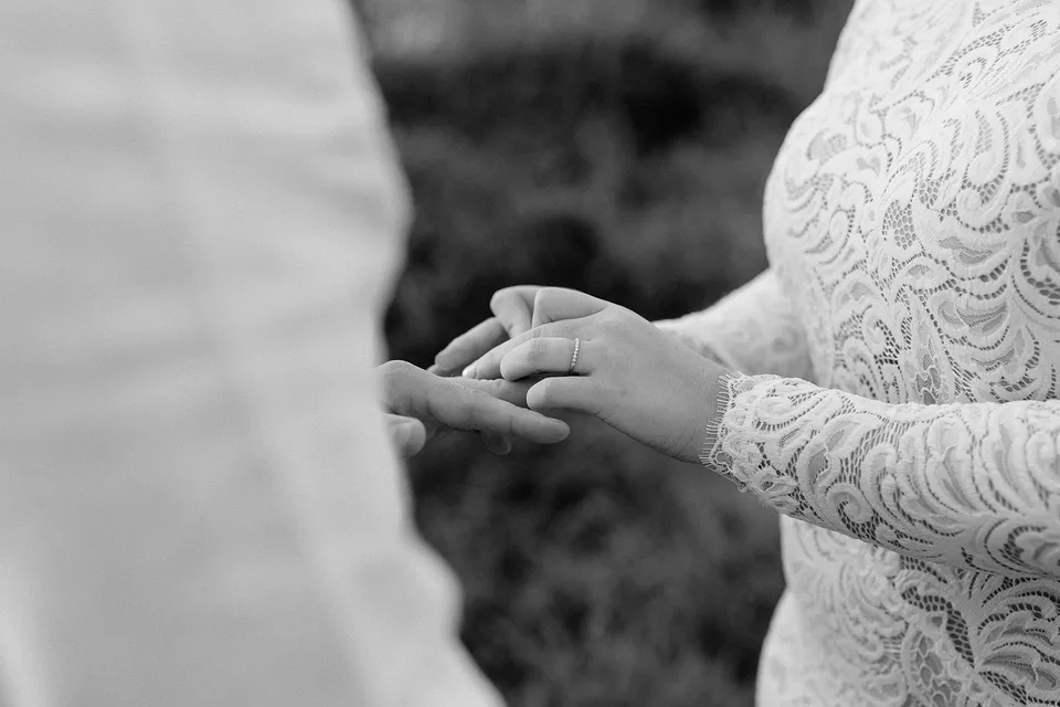 A black and white close-up of Laura placing a wedding ring on Matt’s finger, in the Tweed Valley, NSW, for an Elopement Collective elopement. Photo by Bulb Creative.