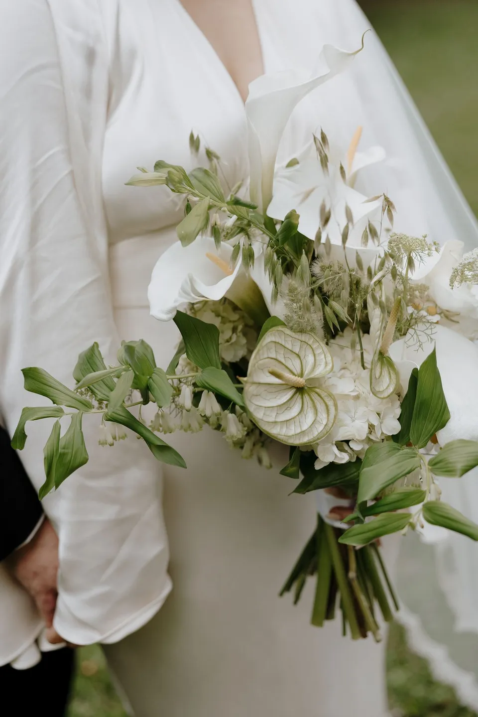 Close-up of The French Petal's white flowers and foliage against Laura's flowing dress. At Fig Tree Villa in Ewingsdale, Byron Bay, for an Elopement Collective elopement. Photograph by George Bowden.
