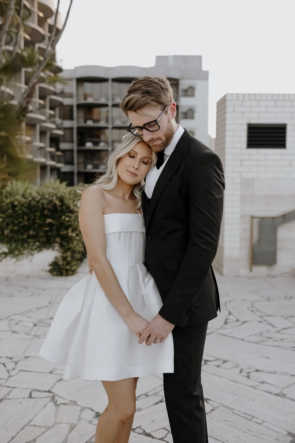 Adam kissing Danielle’s forehead as she leans into him on the stone terrace, during Danielle and Adam’s Elopement Collective elopement at The Calile Hotel in Fortitude Valley, Brisbane.