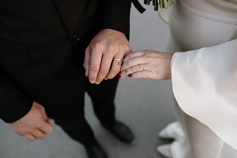 Close view of Kara and Samuel’s hands and wedding rings resting together over a stone bridge balustrade, beside the Seine in Paris, France, during an Elopement Collective elopement. Photograph by George Bowden.