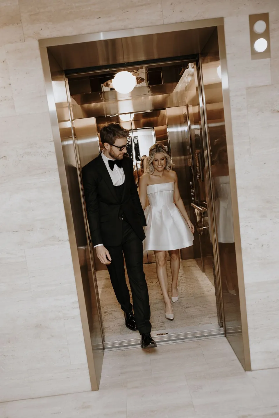 Danielle and Adam stepping out of the hotel’s gold mirrored lift, during Danielle and Adam’s Elopement Collective elopement at The Calile Hotel in Fortitude Valley, Brisbane.