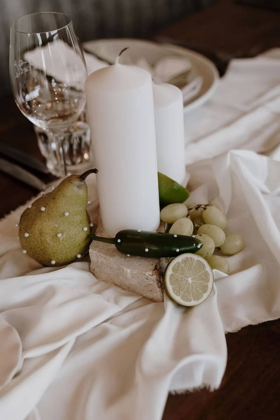 Close-up of candles, green fruit and citrus decorating the reception table. At The Farm and Three Blue Ducks in Ewingsdale, Byron Bay, for an Elopement Collective elopement. Photograph by George Bowden.