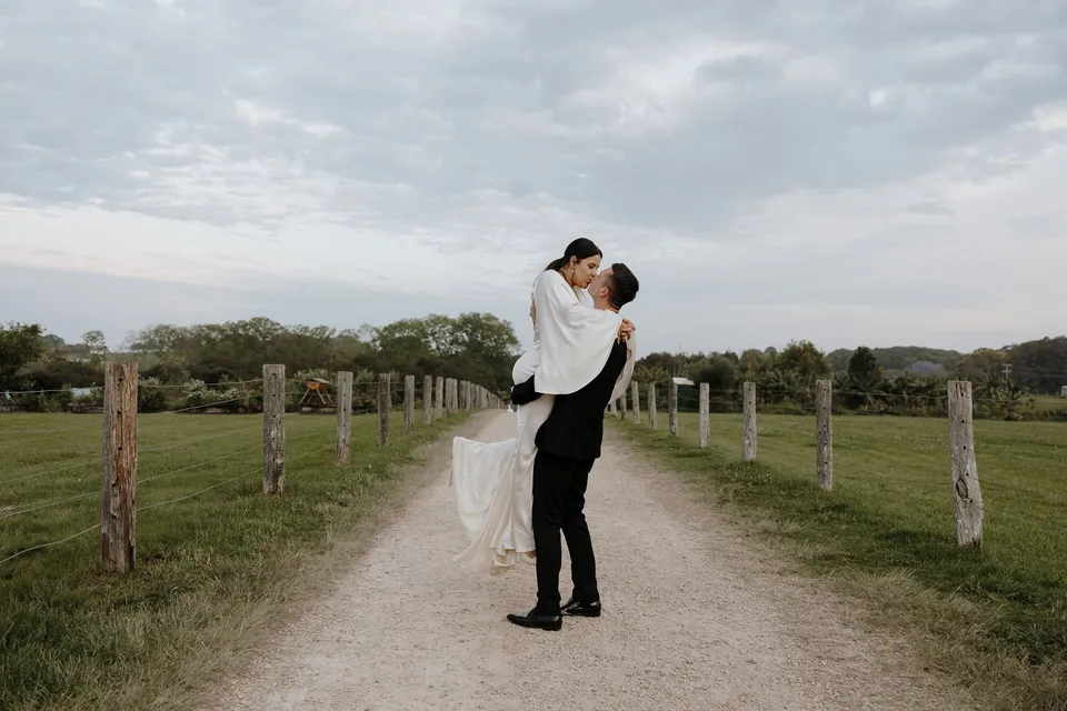 Matthew lifting Laura for a kiss on the farm track. At The Farm and Three Blue Ducks in Ewingsdale, Byron Bay, for an Elopement Collective elopement. Photograph by George Bowden.