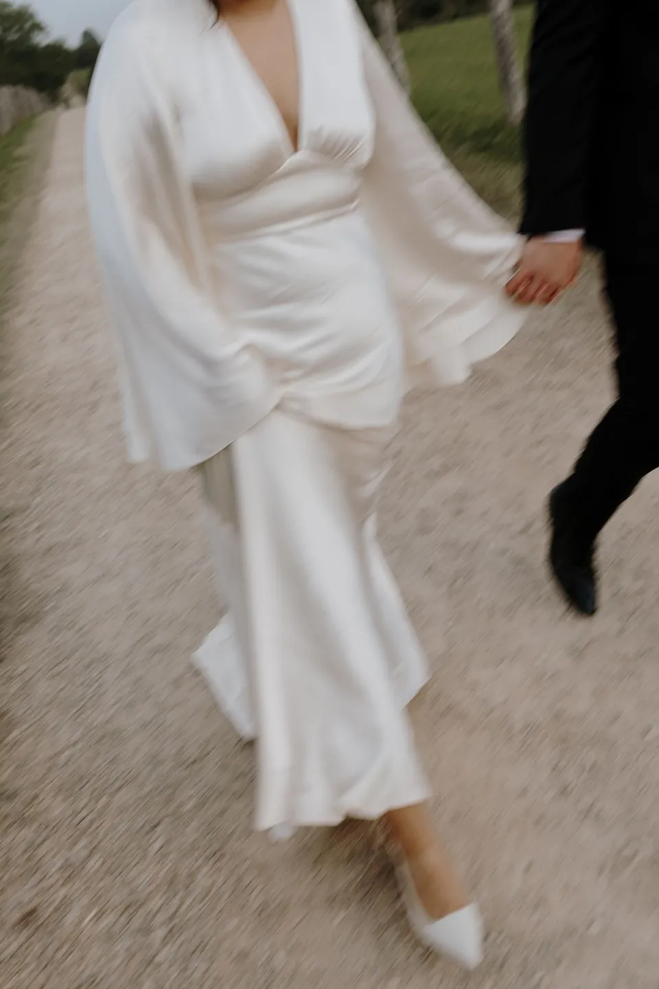 Close-up of Laura's flowing sleeve and dress as she walks beside Matthew. At The Farm and Three Blue Ducks in Ewingsdale, Byron Bay, for an Elopement Collective elopement. Photograph by George Bowden.
