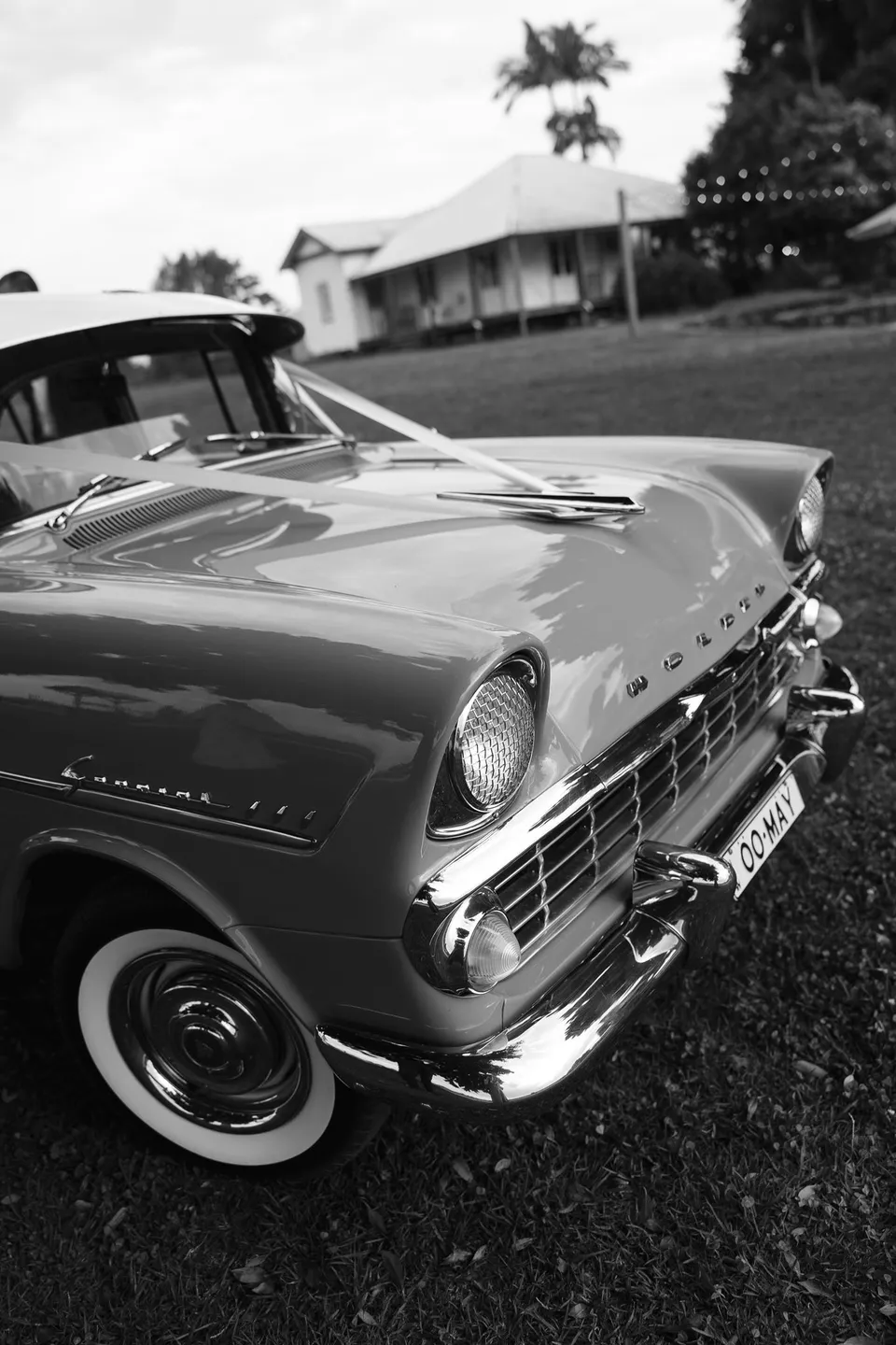 Black-and-white detail of the pink vintage Holden's front grille and chrome trim. At The Farm and Three Blue Ducks in Ewingsdale, Byron Bay, for an Elopement Collective elopement. Photograph by George Bowden.