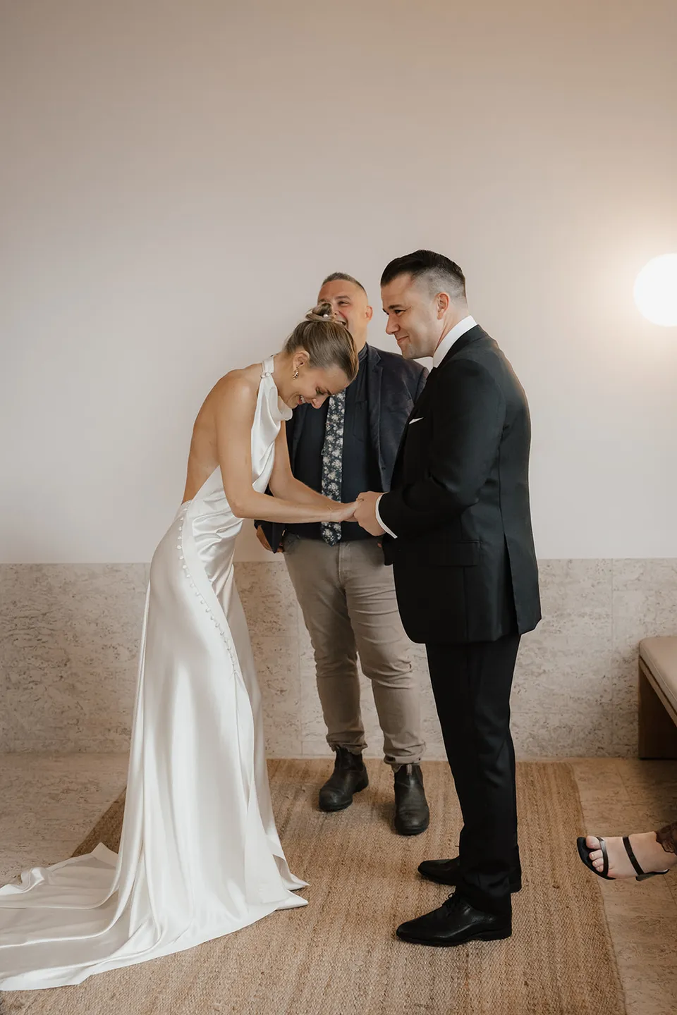 Clare looking down at their hands during the ring exchange, with Josh Withers behind them, at The Calile Hotel in Fortitude Valley for their Elopement Collective Brisbane elopement.