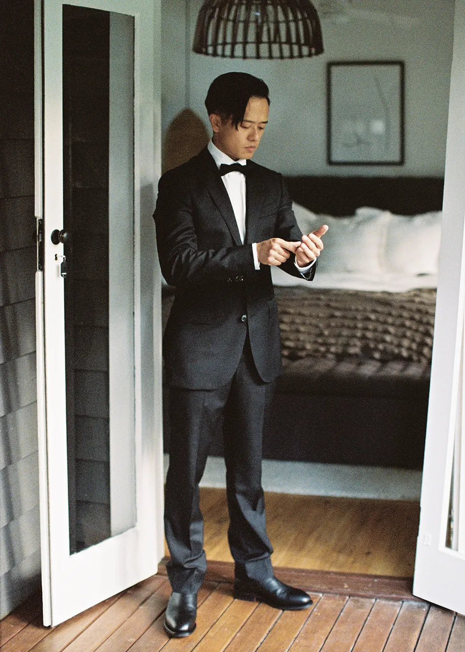 On 35mm film: Full-length portrait of Jonathan getting ready in the bedroom doorway. At Fig Tree Villa in Ewingsdale, Byron Bay, for an Elopement Collective elopement. Photograph by Bulb Creative.