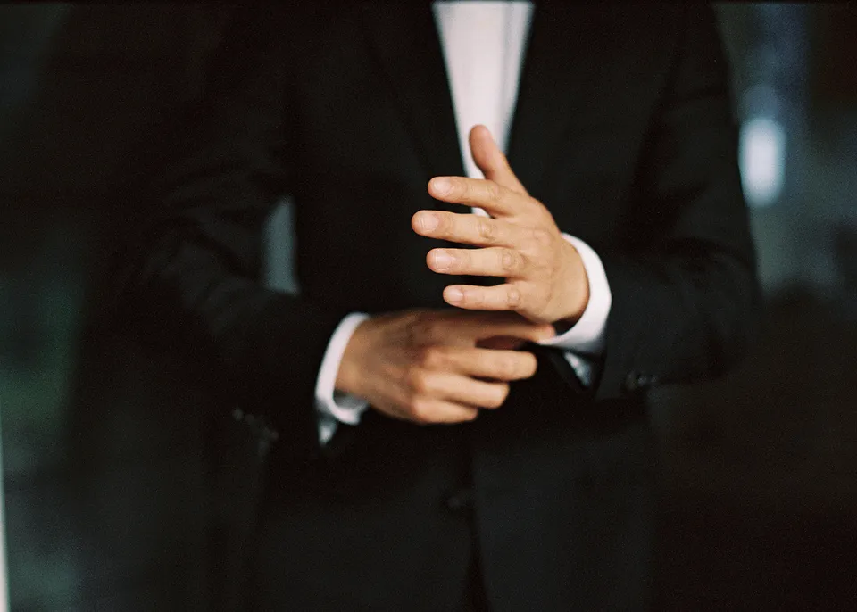 On 35mm film: Close-up of Jonathan fastening his jacket with his wedding band visible. At Fig Tree Villa in Ewingsdale, Byron Bay, for an Elopement Collective elopement. Photograph by Bulb Creative.