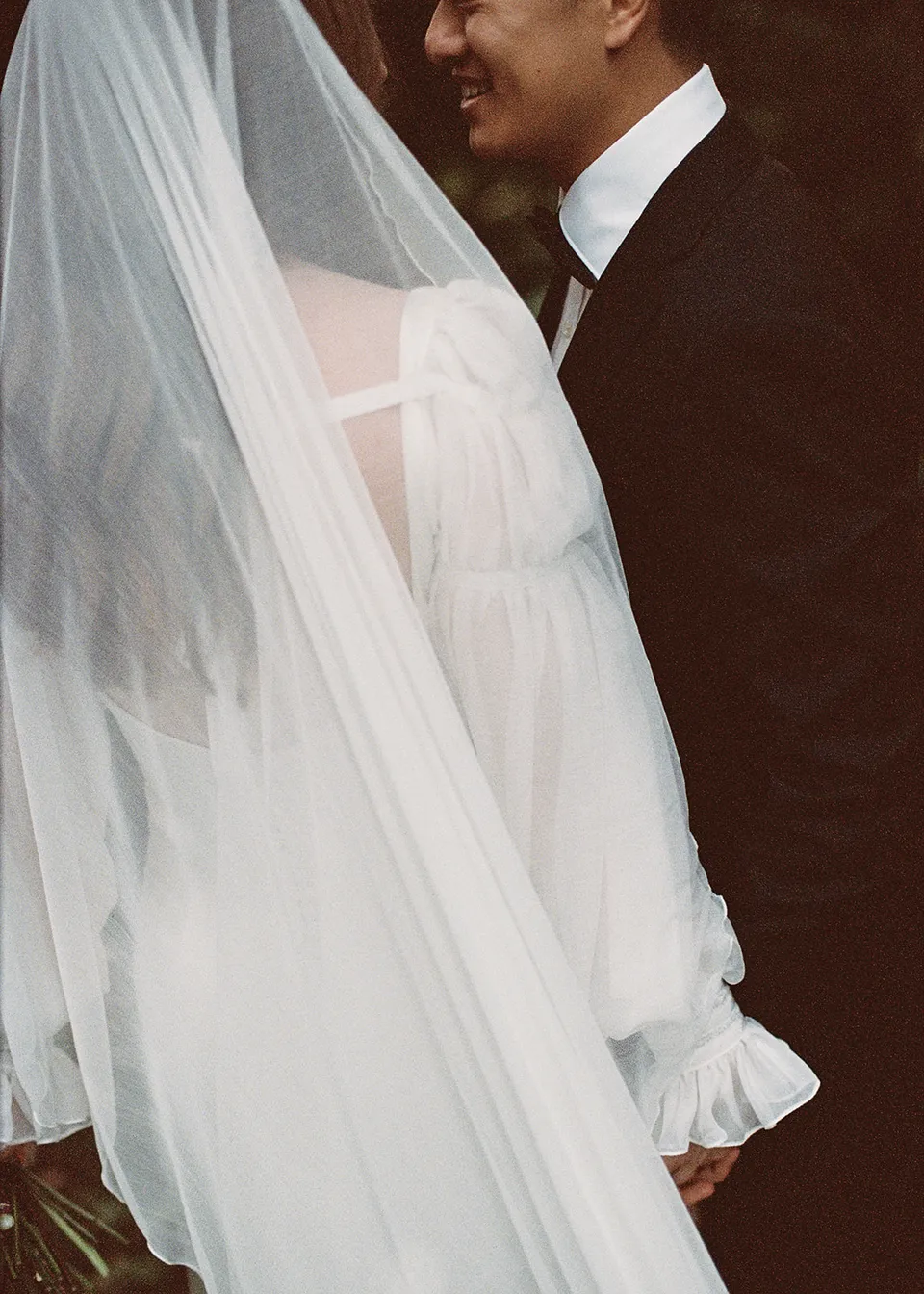On 35mm film: Close view of Elyse's veil as Jonathan leans towards her. At Fig Tree Villa in Ewingsdale, Byron Bay, for an Elopement Collective elopement. Photograph by Bulb Creative.