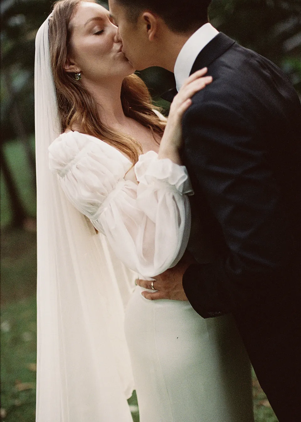 On 35mm film: Close portrait of Elyse leaning towards Jonathan for a kiss. At Fig Tree Villa in Ewingsdale, Byron Bay, for an Elopement Collective elopement. Photograph by Bulb Creative.