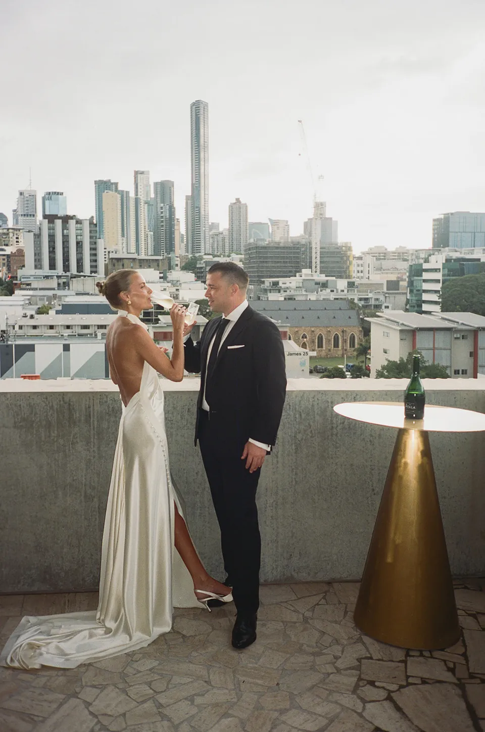 Clare and Matt facing each other on a terrace overlooking Brisbane at The Calile Hotel in Fortitude Valley during their Elopement Collective elopement.