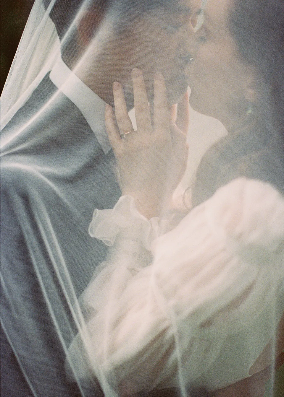 On 35mm film: soft close-up of the couple kissing beneath the sheer veil. At Fig Tree Villa in Ewingsdale, Byron Bay, for an Elopement Collective elopement. Photograph by Bulb Creative.