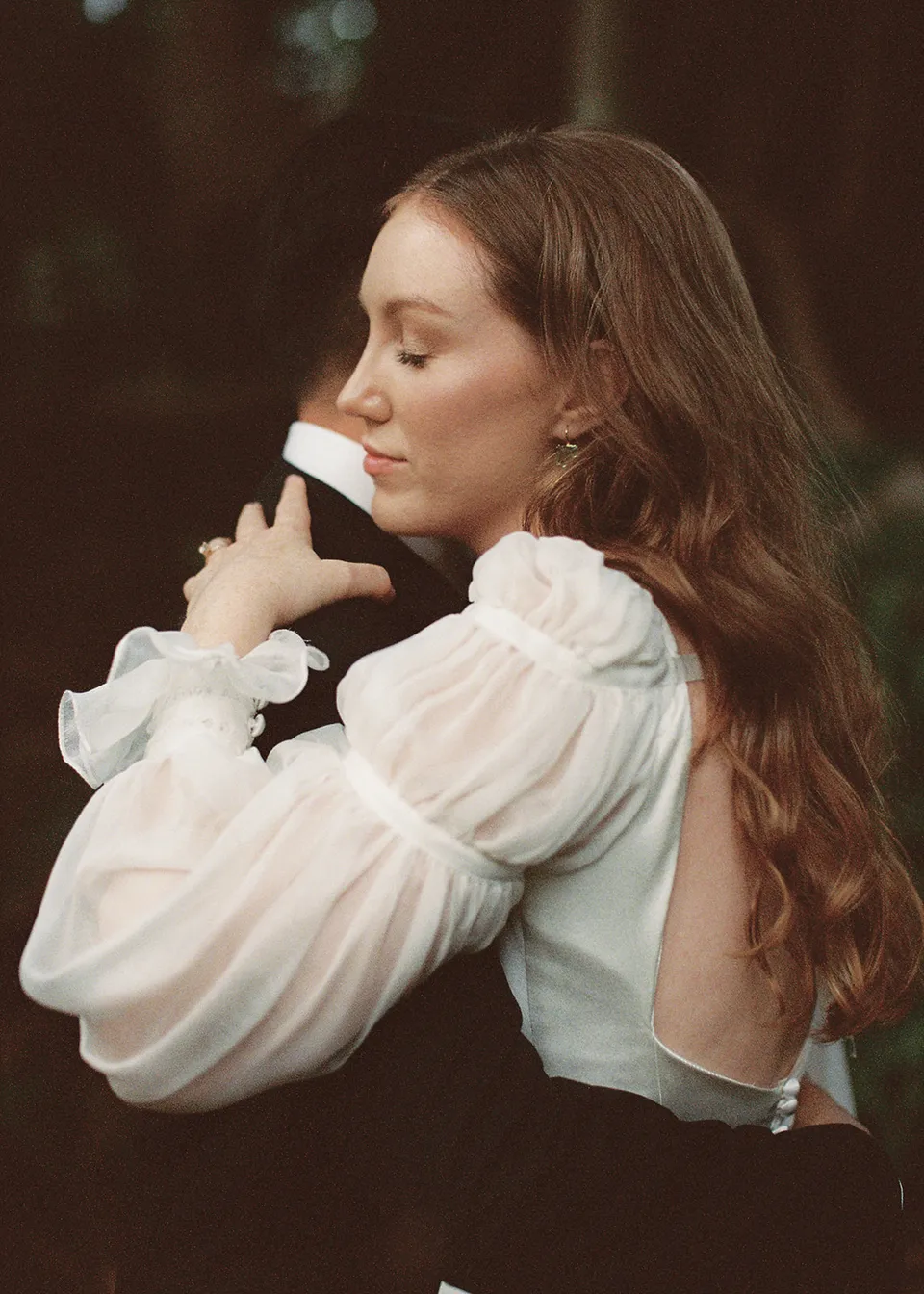 On 35mm film: Elyse closing her eyes while holding Jonathan beneath the trees. At Fig Tree Villa in Ewingsdale, Byron Bay, for an Elopement Collective elopement. Photograph by Bulb Creative.