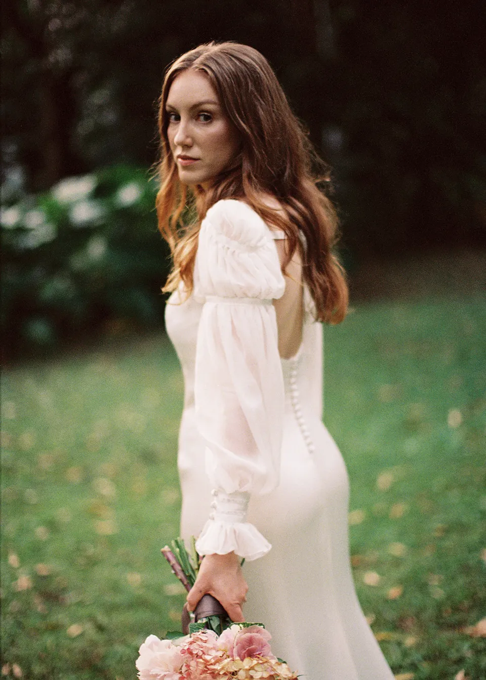 On 35mm film: Close portrait of Elyse looking over her shoulder in the garden. At Fig Tree Villa in Ewingsdale, Byron Bay, for an Elopement Collective elopement. Photograph by Bulb Creative.