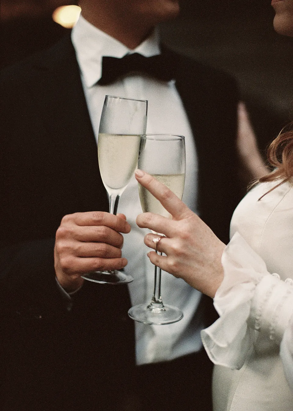 On 35mm film: Close-up of the couple toasting with sparkling wine. At Fig Tree Villa in Ewingsdale, Byron Bay, for an Elopement Collective elopement. Photograph by Bulb Creative.