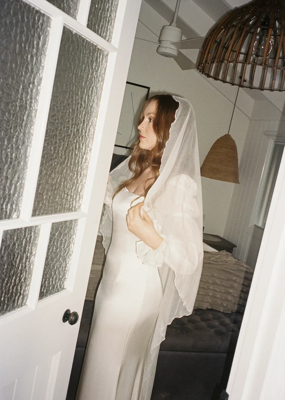 On 35mm film: Elyse looking outside from the bedroom doorway. At Fig Tree Villa in Ewingsdale, Byron Bay, for an Elopement Collective elopement. Photograph by Bulb Creative.