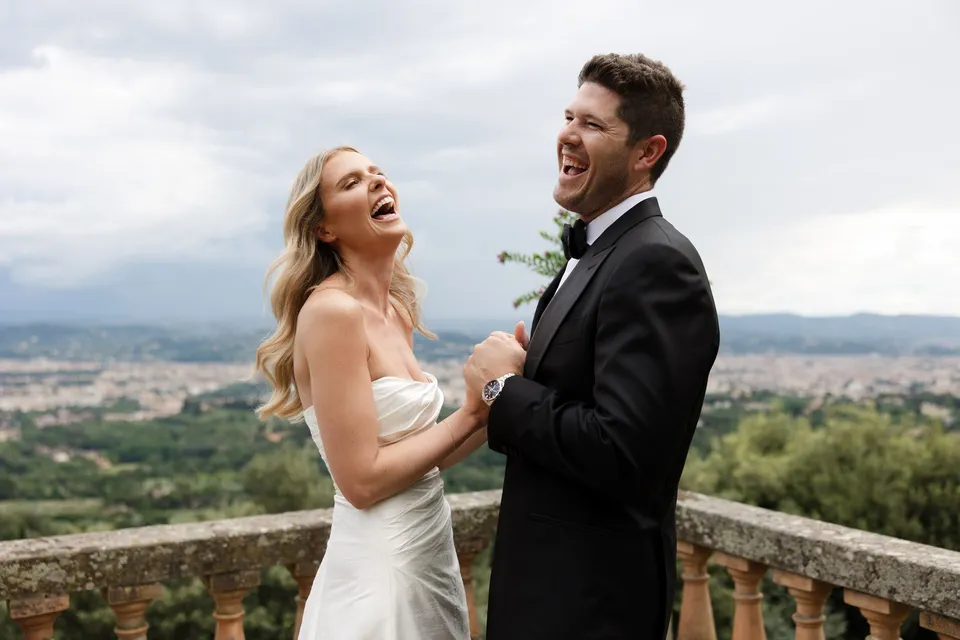 Holly and Matthew laughing together on the terrace at Villa San Michele in Fiesole above Florence, Tuscany, Italy, with Holly’s bridal makeup by Shannon Hope, for an Elopement Collective elopement. Photograph by Khara from House of Lucie.