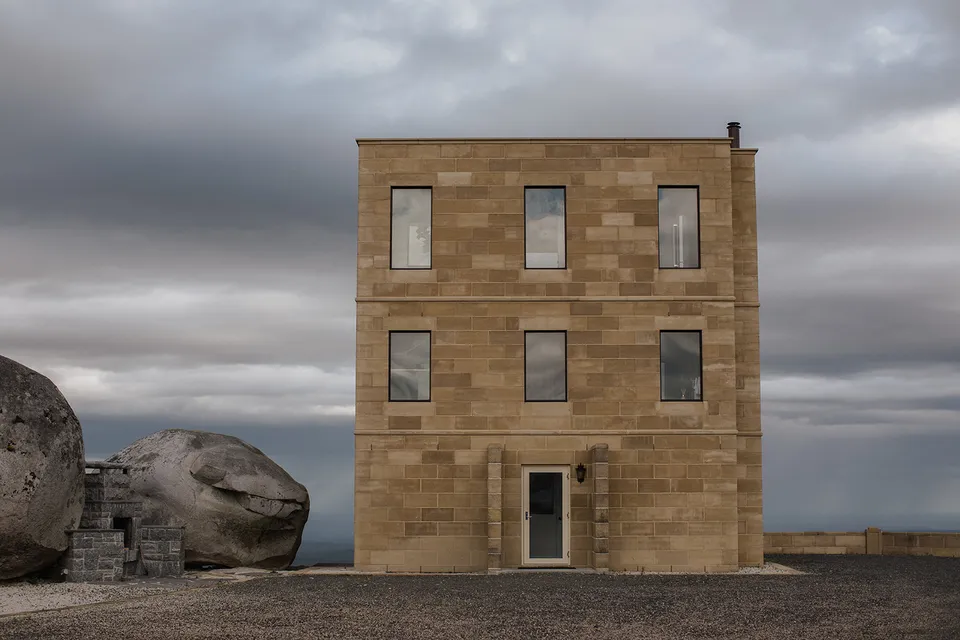The Keep’s three-storey sandstone tower beside enormous granite boulders under a cloudy sky in Goulds Country, Tasmania, an Elopement Collective venue. Photograph by Jenna Agius.
