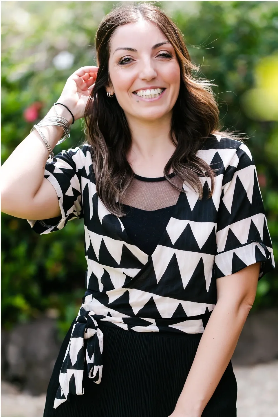 Valentina Pintus of Sunshine Brides smiling outdoors in a black and white patterned top. Portrait by Lou O’Brien.