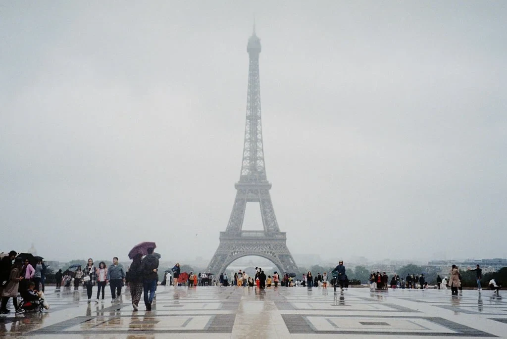 People walking on a rainy day near the Eiffel Tower in Paris.
