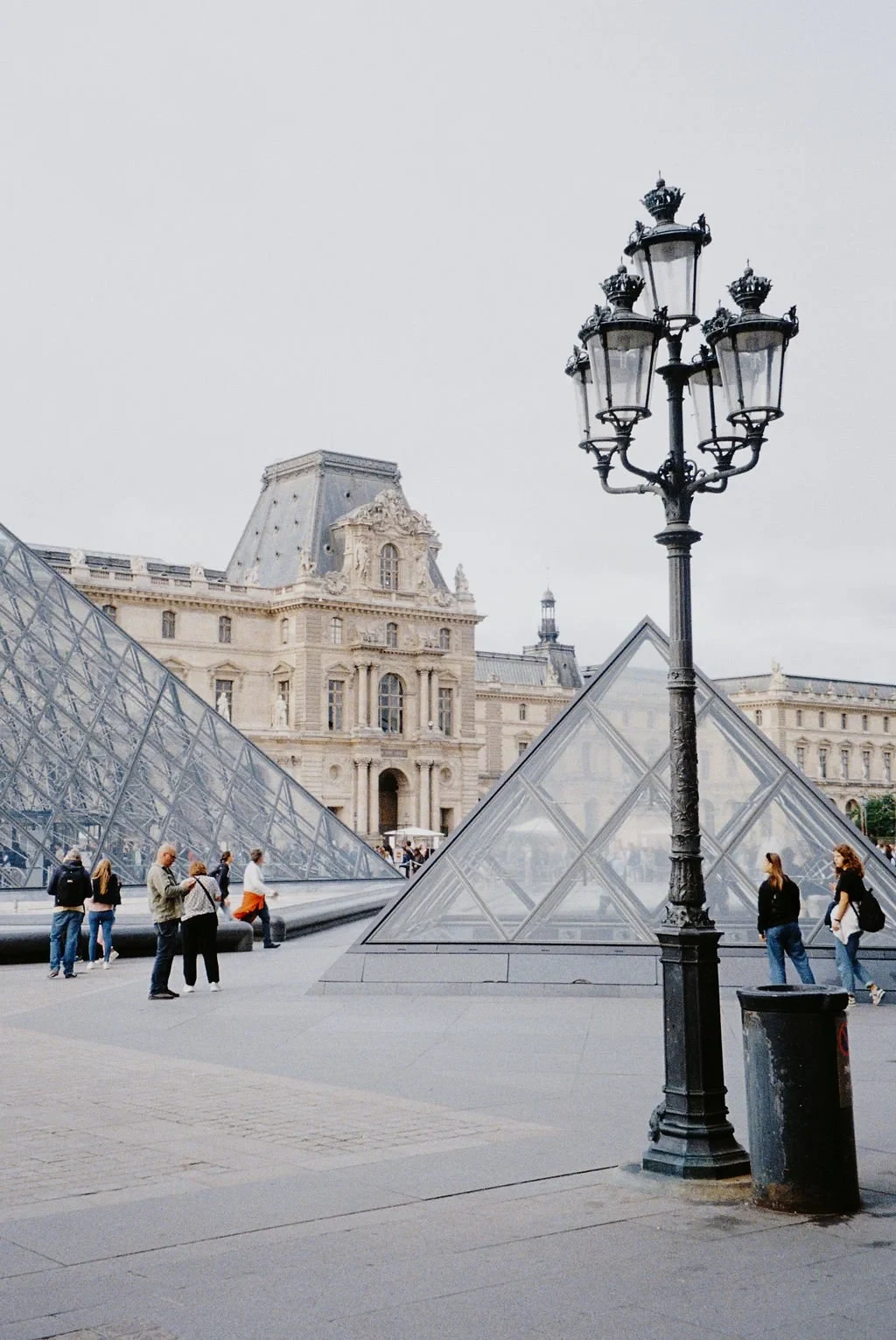Louvre Museum Paris with glass pyramids and vintage lamp post