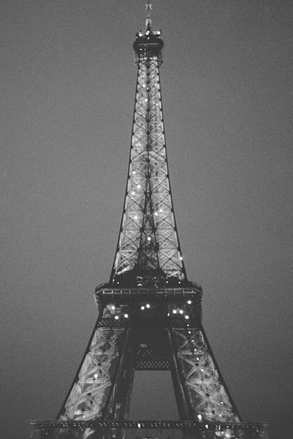 Black and white photo of the Eiffel Tower illuminated at night.