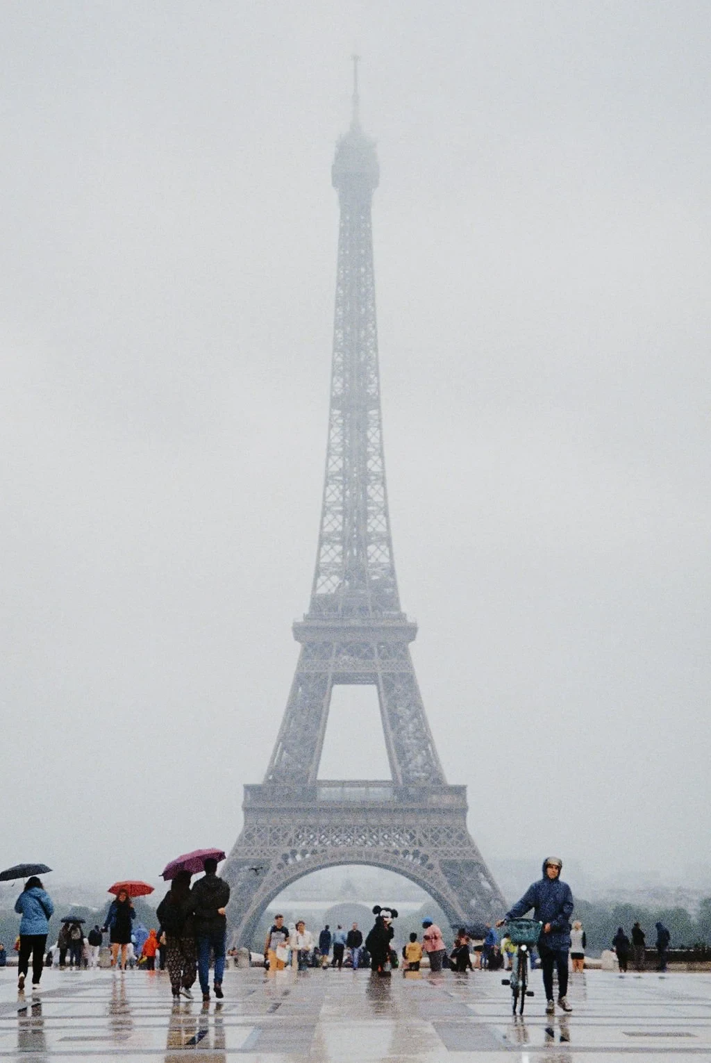 Eiffel Tower on a foggy day with people holding umbrellas