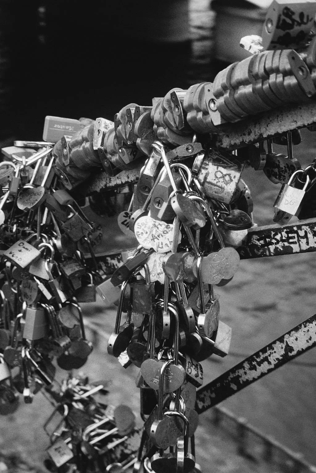 Close-up of love locks attached to a bridge railing, black and white photo.