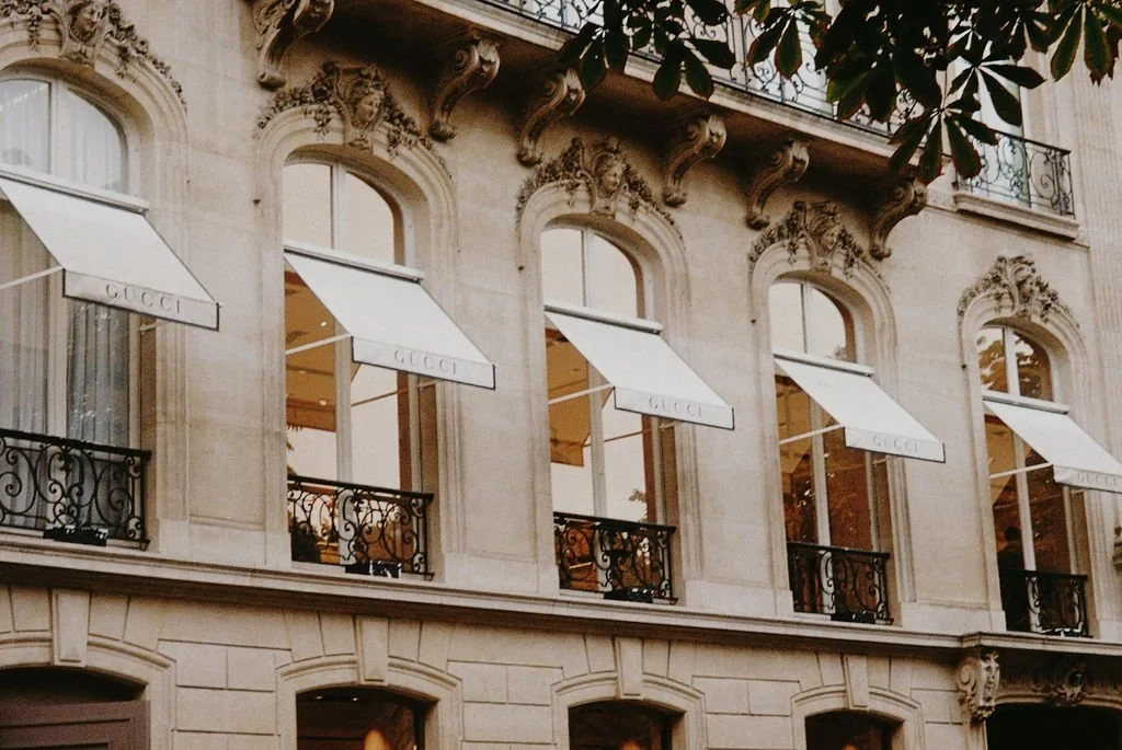 Elegant building facade with classic window awnings labeled "Gucci."