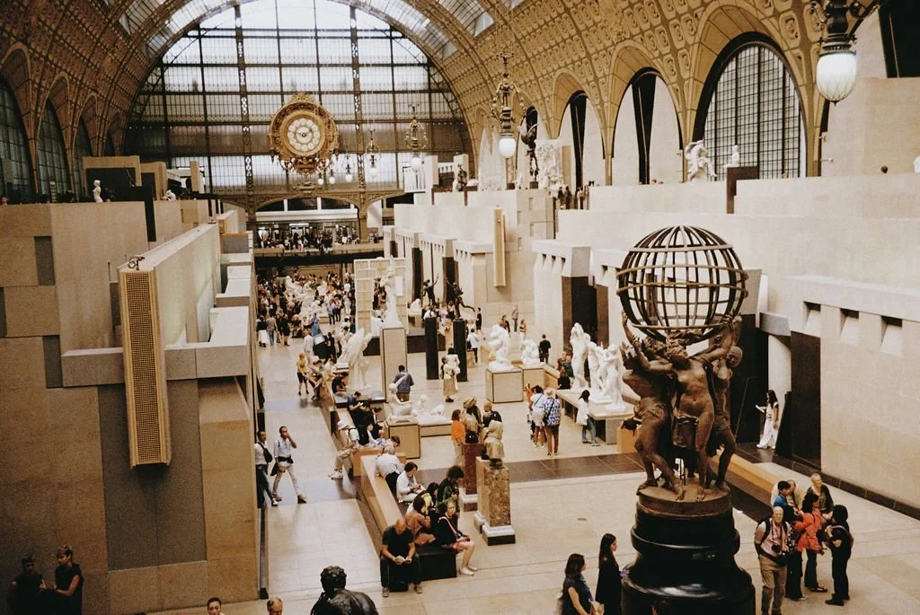 Interior of a museum with classical sculptures and a large clock.