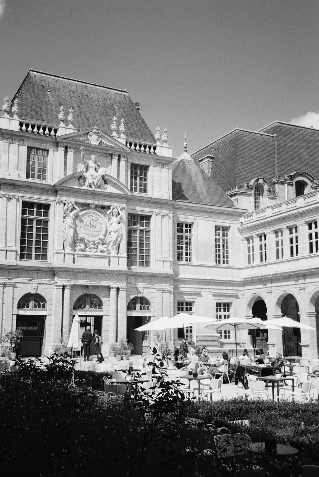Historic European building with outdoor cafe tables and people.