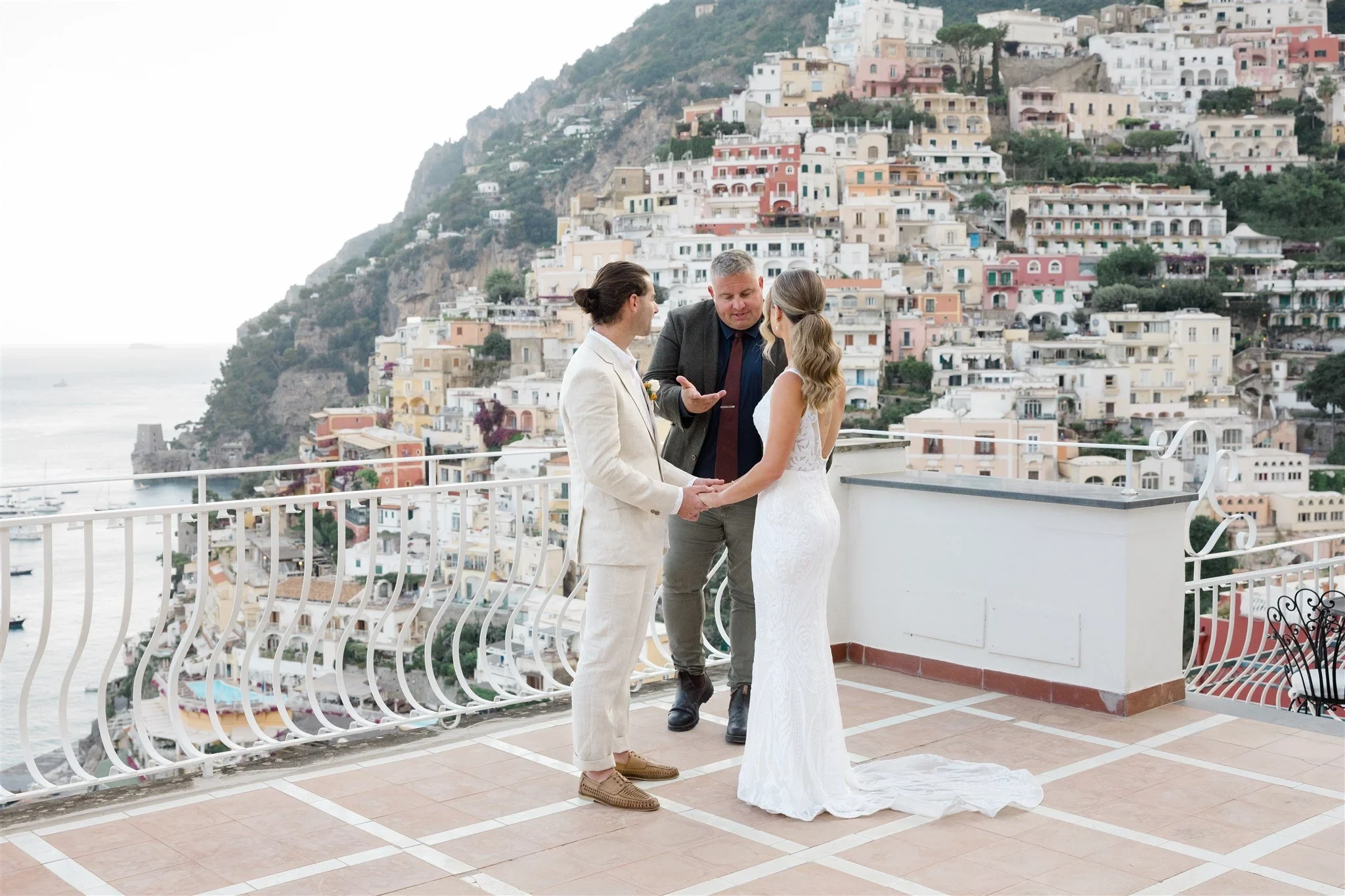 Sarah and Josh holding hands during their terrace ceremony with celebrant Josh Withers, at Alcione Residence in Positano, Amalfi Coast, Italy, for an Elopement Collective elopement. Photo by James from House of Love.