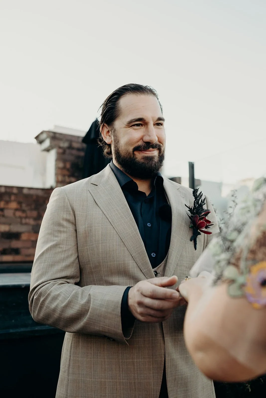 Daniel smiling at Victoria during their rooftop ring exchange, at Agnes Restaurant in Fortitude Valley, Brisbane, for an Elopement Collective elopement. Photo by Tessa Shannon.